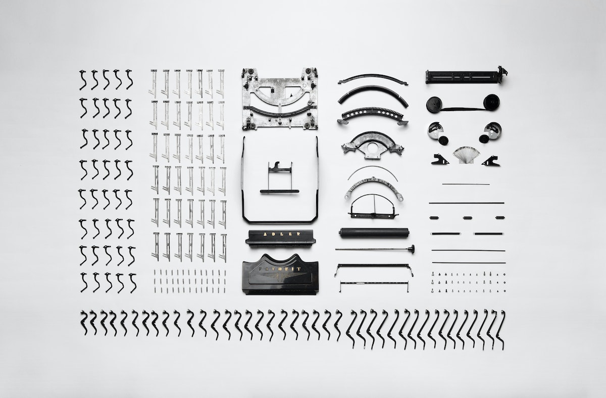 The parts of a disassembled typewriter laid out in neat rows